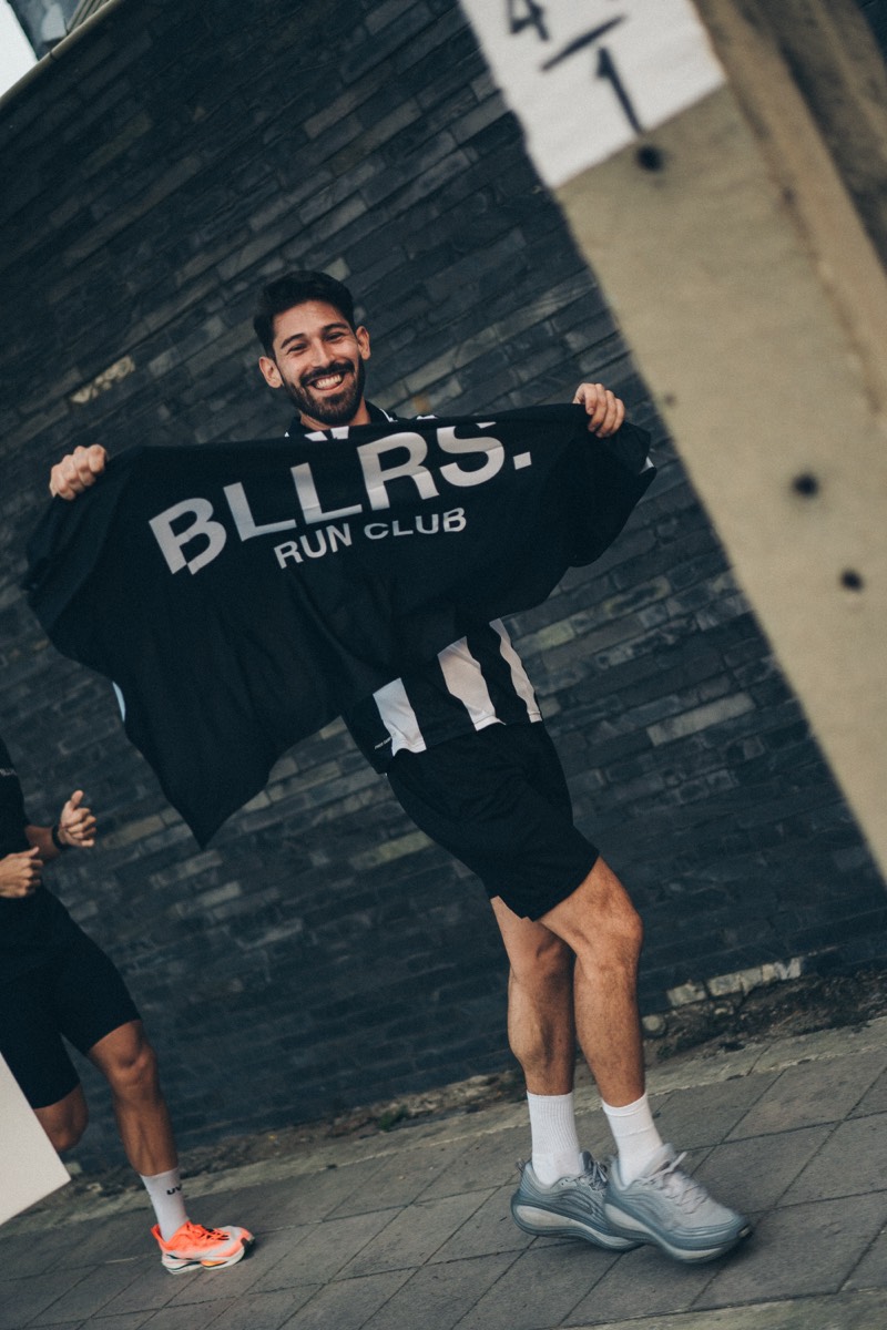 A runner holding up the BLLRS. Run Club shirt